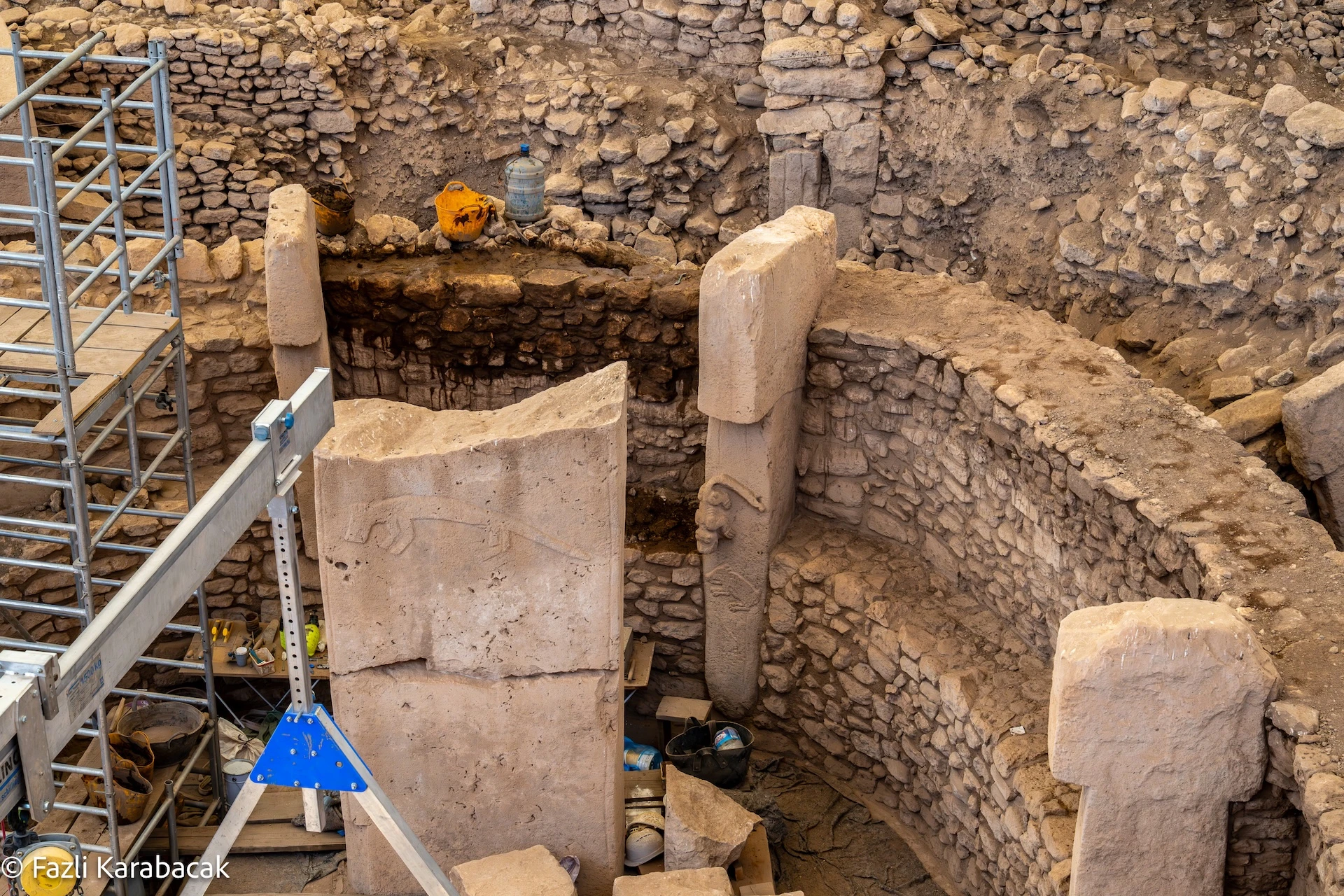 Overhead view of an excavated enclosure at Göbekli Tepe showing multiple animal carvings on T-shaped pillars