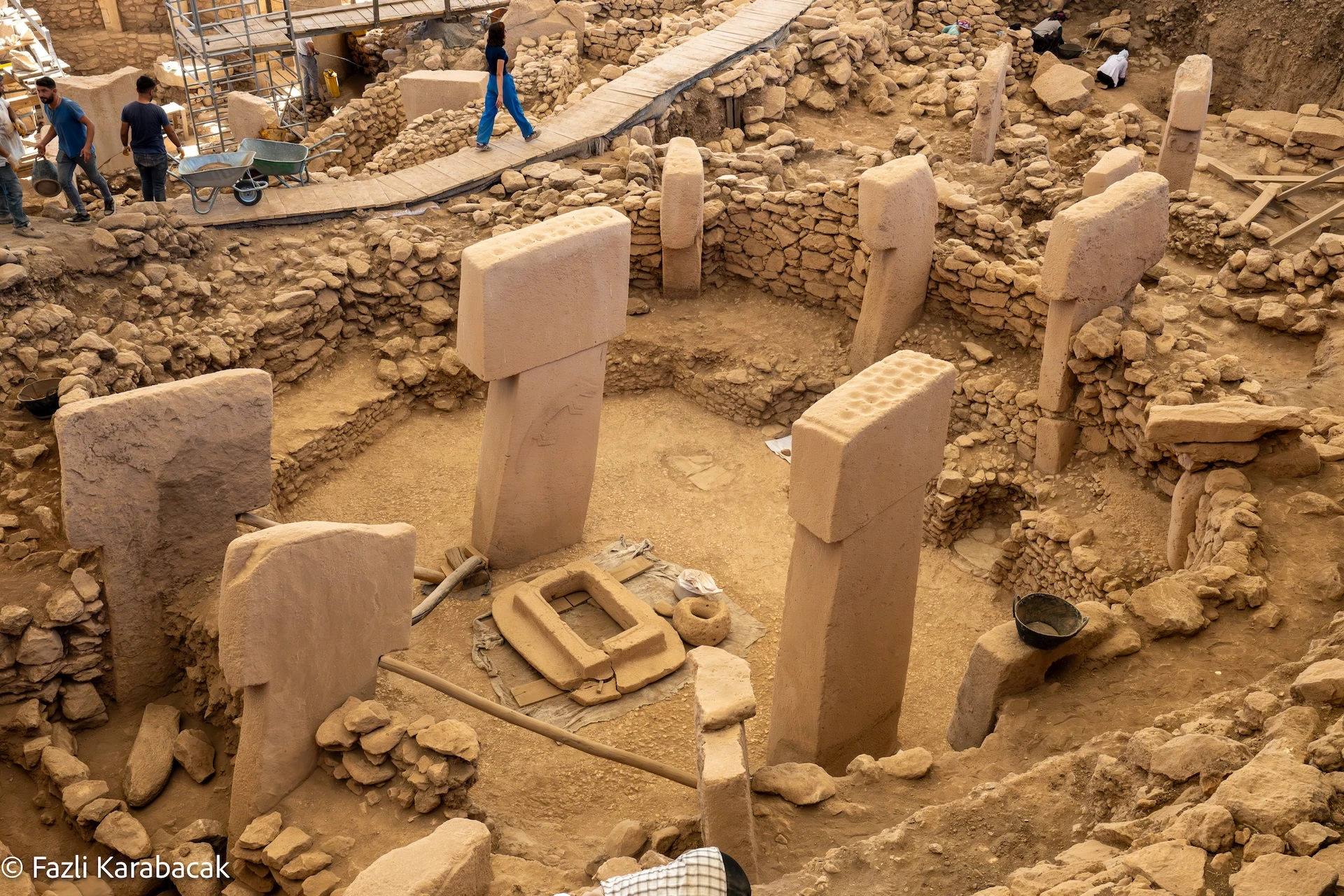 Göbekli Tepe's enclosures in early morning light — the T-shaped pillars casting long shadows across bedrock